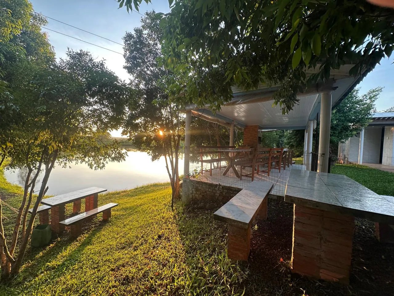 Área de lazer com mesas e vista para o açude ao entardecer